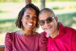 image of smiling woman wearing red shirt posed with a man in sunglasses and red collard shirt